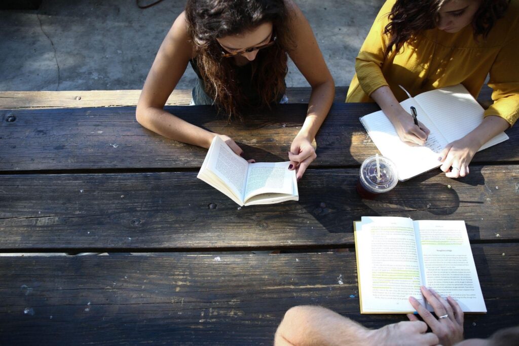 Students sitting outdoors and writing in their notebooks