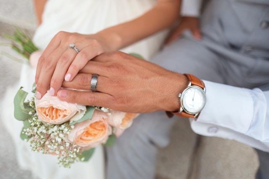 A man and a woman holding hands, with wedding rings on their ring fingers