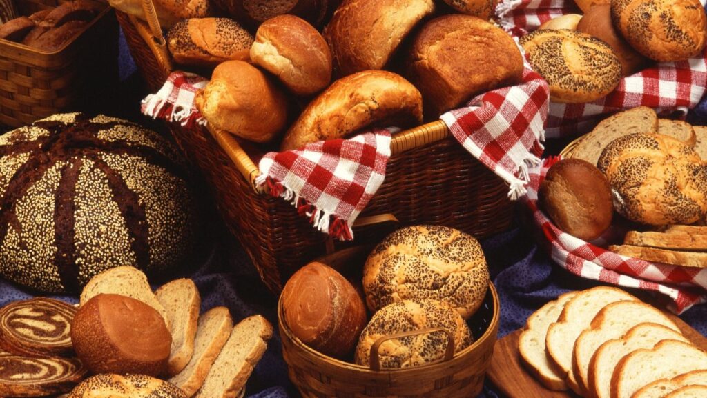 Loaves of bread, baguettes, and other baked goods in a basket.