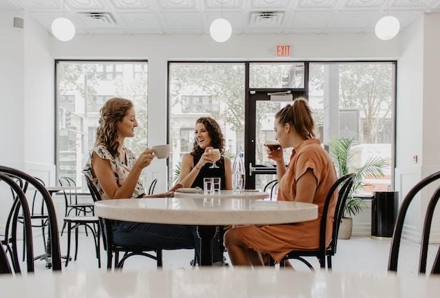 Three women drinking coffee at a cafe.