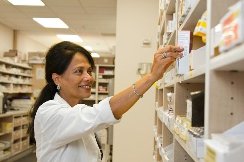 A woman in a pharmacy holding a box.