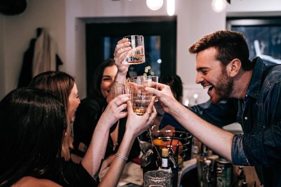 A group of students toasting with whiskey glasses at a party