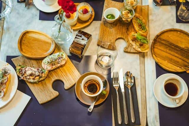 Two cups of black coffee, sandwiches, and dessert on a table at a restaurant.