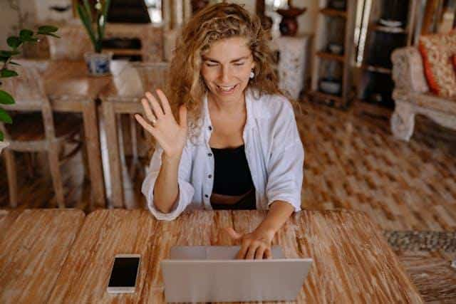 A woman smiling while practicing Serbian pronunciation with an online teacher.