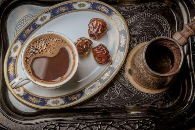 A cup of coffee with dates on a serving tray.