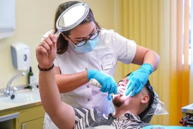 A dentist working on a young man's tooth.