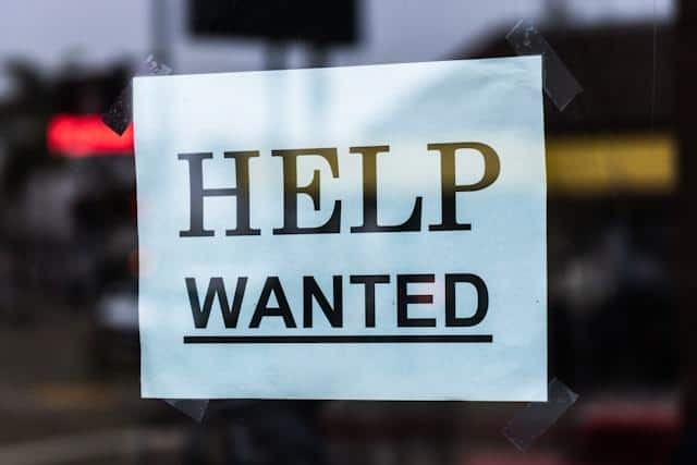 A piece of paper with help wanted written on it.