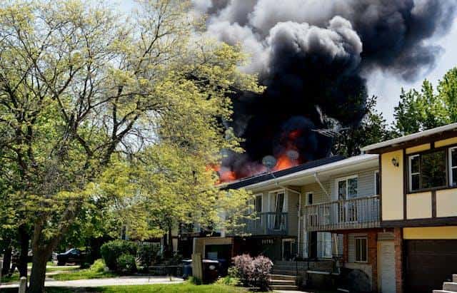 A house on fire, with black smoke rising