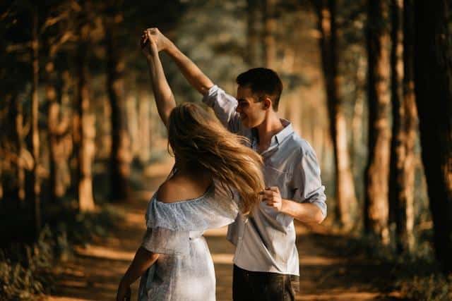 A woman and a man dancing in a forest.