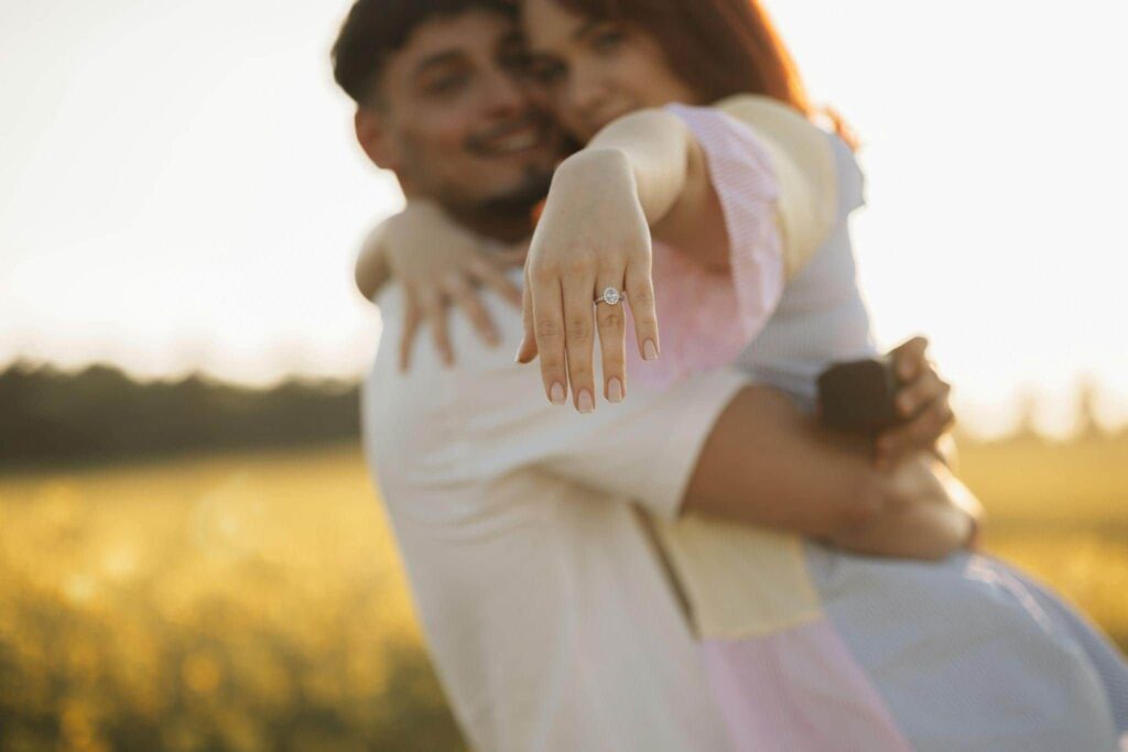 A man hugging a woman with an engagement ring on her finger.