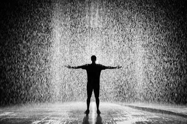 A man standing under the heavy rain.