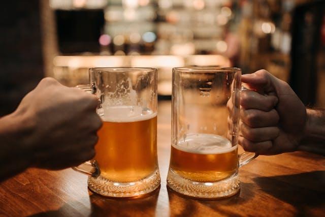 Two people holding jugs of beer.