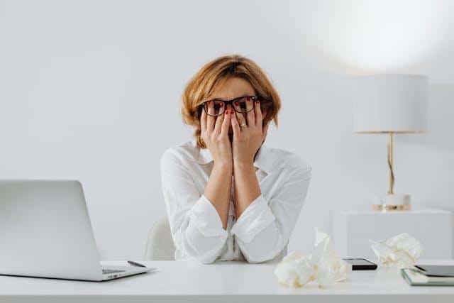 A counter clerk rubbing her eyes, looking annoyed.