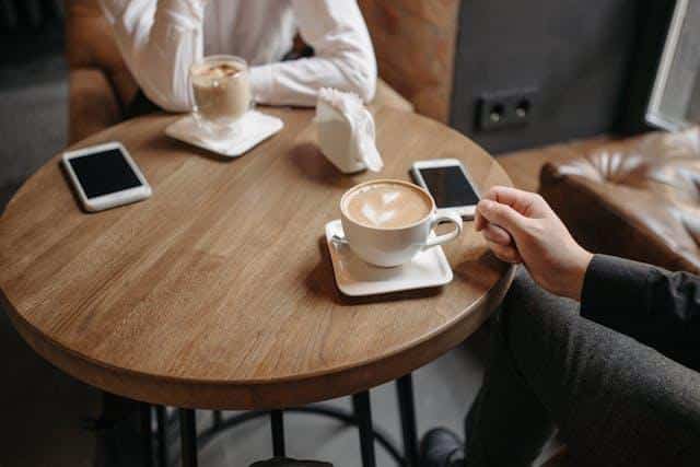 A man and a woman sitting at a cafe with coffee cups in front of them — an illustration of Serbian dating culture.