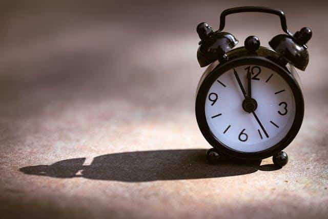 An old-fashioned clock on a clear surface illustrating time expressions in Serbian.