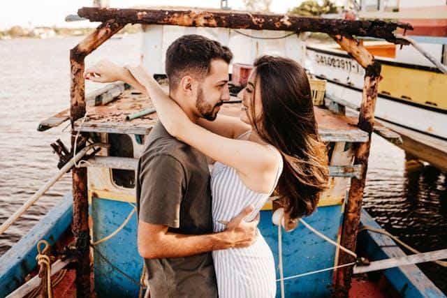 A man and a woman on a boat, hugging.