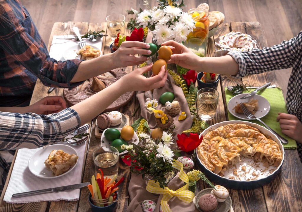 Friends gathered over an Easter spread, holding colorful eggs