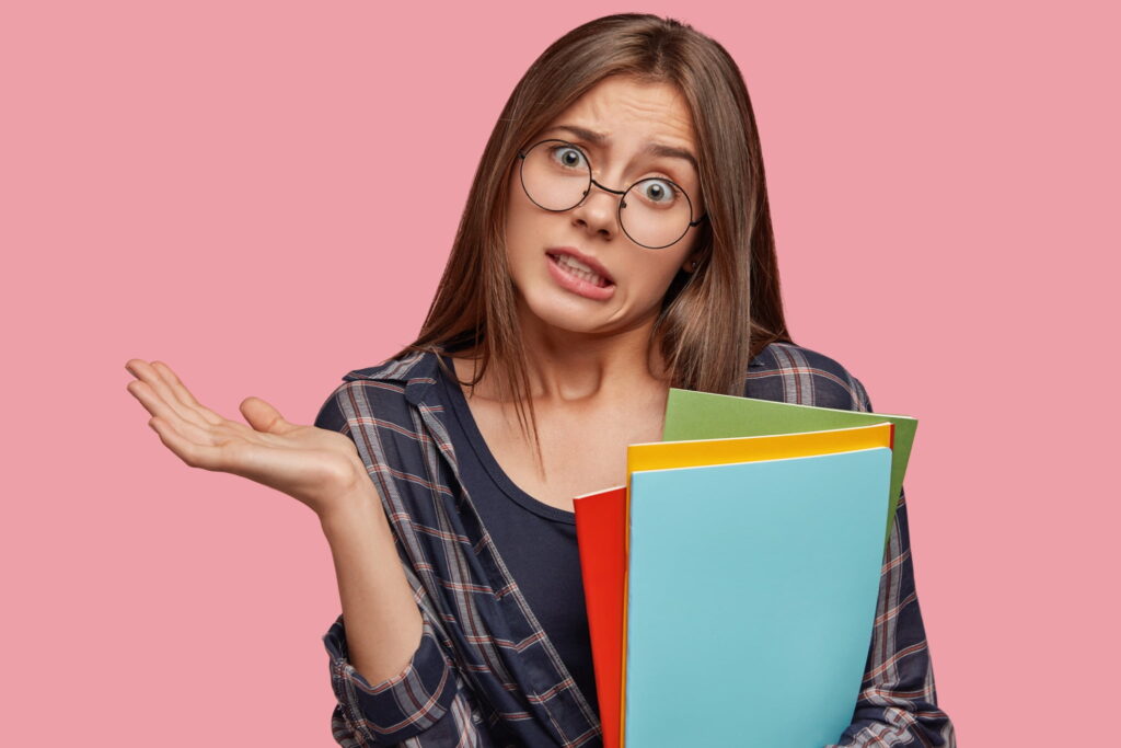 A confused woman holding notebooks in different colors