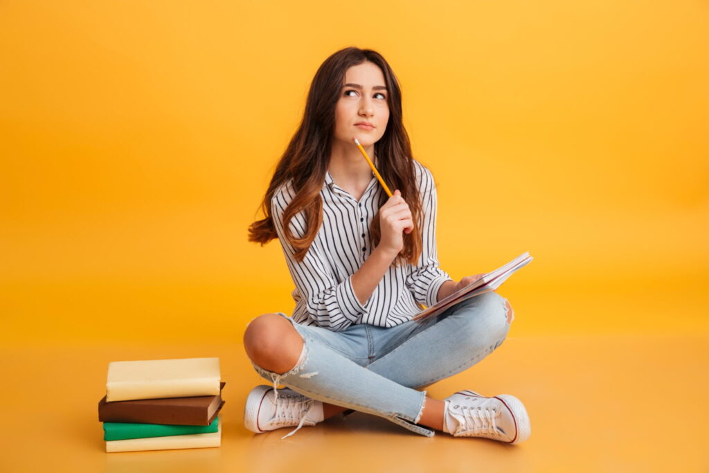 A girl studying Serbian nouns with a pile of books next to her
