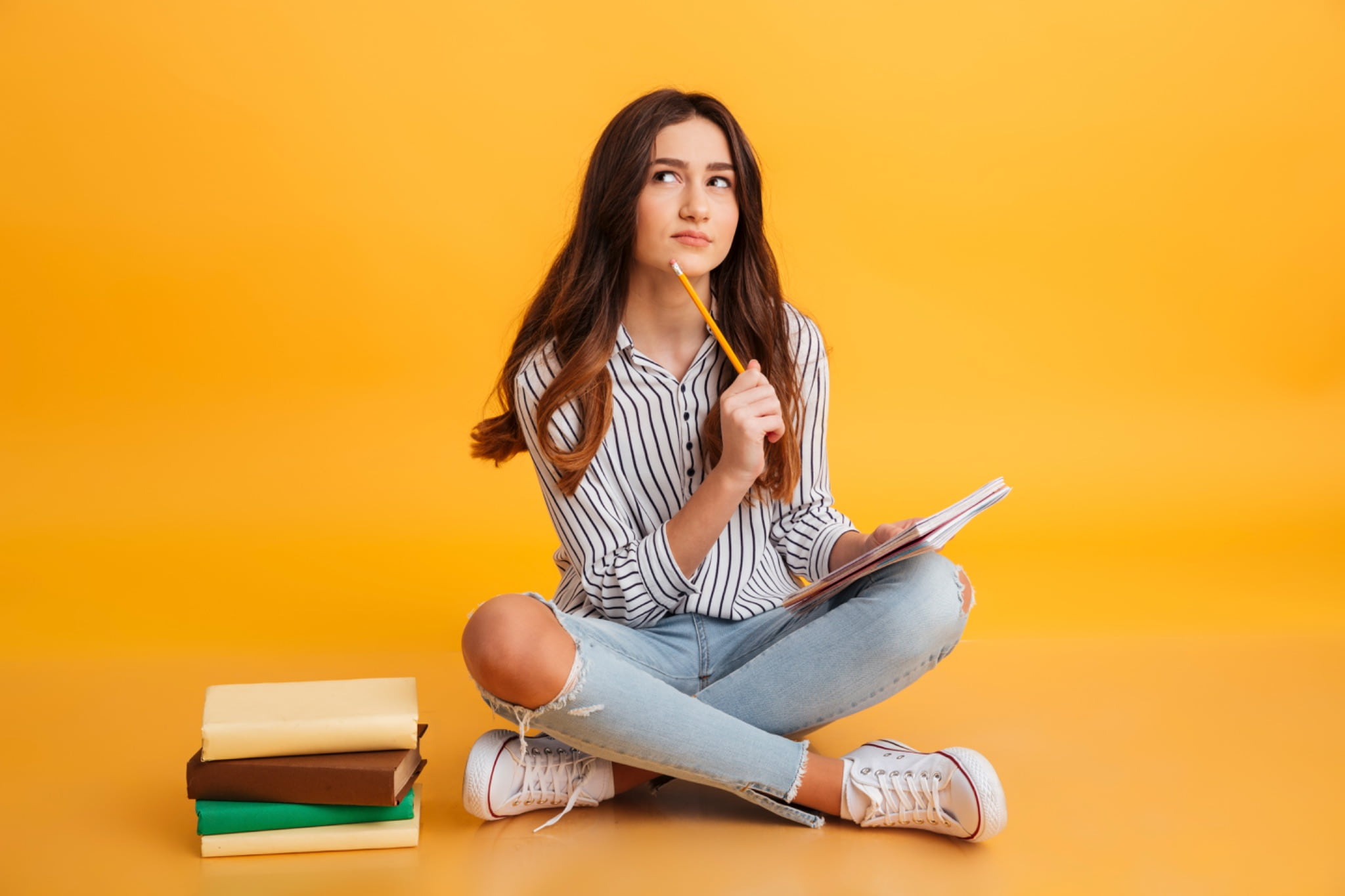 A girl studying Serbian nouns with a pile of books next to her