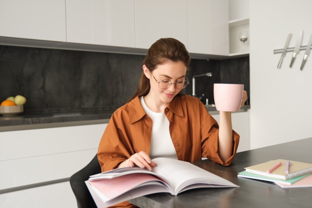 A young woman studying at home and drinking coffee