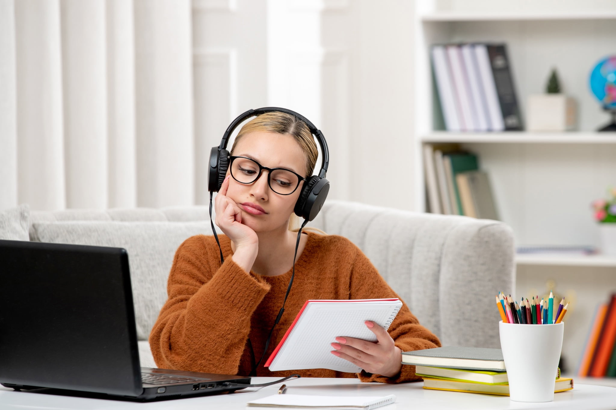 A young woman studying with a set of headphones